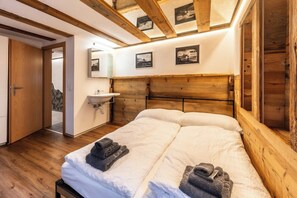 Ein Hotelzimmer mit einem hölzernen Kopfteil, einem Doppelbett, einem Nachttisch, einem Waschbecken und einem Spiegel.