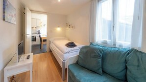 A bedroom with a bed, a desk with a computer, a window with curtains, and a view of a kitchen. - Where Comfort Meets Luxury, Wallis 1081 (Wallis)
