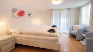 A hotel room with a bed, bedside tables, a chair, and a window with curtains. - Where Comfort Meets Luxury, Wallis 1081 (Wallis)
