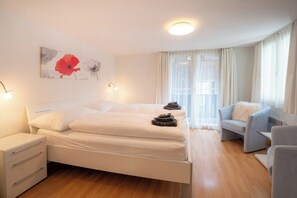 Ein Hotelzimmer mit Bett, Nachttischen, einem Sessel und einem Fenster mit Vorhängen.