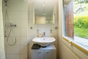 Ein Badezimmer mit einem weißen Waschbecken, einem Spiegel und einer Dusche.