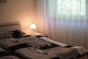 A hotel room with a bed, a nightstand, a lamp, and sheer curtains. - Elegant Mountain Escape, Wallis 1072 (Wallis)