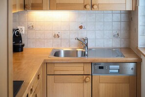 A kitchen with a stainless steel sink, wooden cabinets, and a dishwasher. - Elegant Mountain Escape, Wallis 1072 (Wallis)
