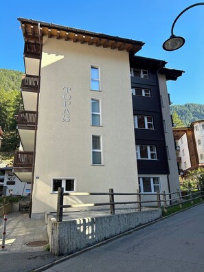 Ein mehrgeschossiges Gebäude mit beige farbenem Mauerwerk, Balkonen und einem Schild mit der Aufschrift 'TOPOA S'.