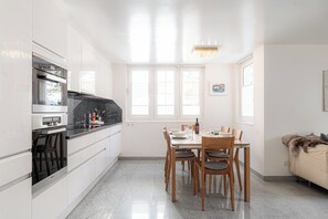 Eine moderne Küche mit weißen Schränken, einer schwarzen Arbeitsplatte und einem Essbereich mit Holztischen und einem Tisch.