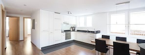 A modern kitchen with white cabinets, a black countertop, and a dining area with a table and chairs. - Your Cozy Luxury Escape, Wallis 1074 (Wallis)
