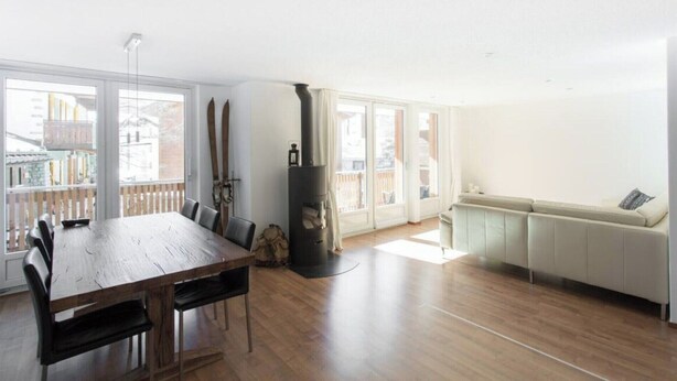 Ein geräumiger Wohnbereich mit einem Holzesstisch, einer Couch und einem Kamin.