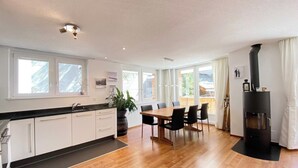 Eine moderne Küche mit Essbereich, großen Fenstern und einem Kaminofen.