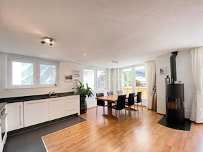 A modern kitchen with a dining area, large windows, and a wood-burning stove. - Your Cozy Luxury Escape, Wallis 1074 (Wallis)
