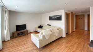 Ein modernes Wohnzimmer mit einer Couch, einem Fernseher und einer Holzunterhaltungsecke.