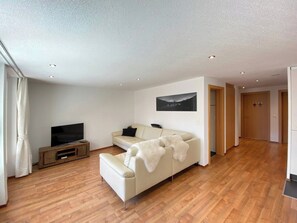 A modern living room with a sofa, a TV, and a wooden entertainment unit. - Your Cozy Luxury Escape, Wallis 1074 (Wallis)