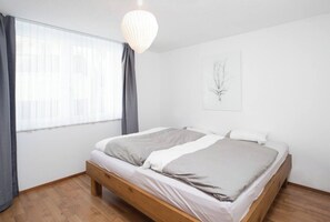 A bedroom with a wooden bed, a window with curtains, and a hanging light fixture. - Your Cozy Luxury Escape, Wallis 1074 (Wallis)