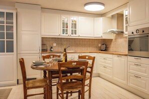 Una cocina moderna con armarios blancos, una mesa de comedor de madera y un horno empotrado.