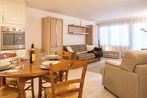 A modern living room with a dining area, wooden furniture, and a built-in kitchen. - Mountain Bliss Awaits, Wallis 1075 (Wallis)