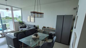 Eine moderne Küche mit Essbereich, ausgestattet mit einem Glastisch, dunklen Stühlen und einer hängenden Leuchte.