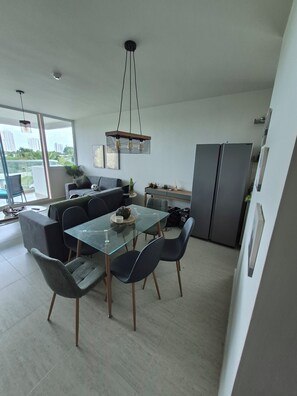 A modern kitchen with a dining area, featuring a glass-top table, dark chairs, and a hanging light fixture. - Luxury Beach Condo in Playa Blanca | Saltwater Lagoon Access | Sleeps 6 (Río Hato)