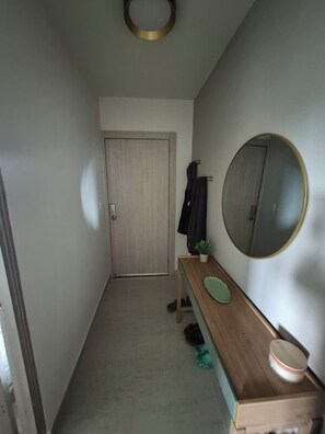 A narrow hallway with a wooden bench, a round mirror, and a door at the end. - Luxury Beach Condo in Playa Blanca | Saltwater Lagoon Access | Sleeps 6 (Río Hato)