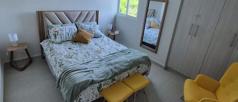 A bedroom with a bed, bedside tables, a mirror, a wardrobe, and a window.