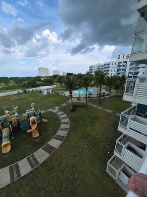 A residential area with a swimming pool, palm trees, and a playground. - Luxury Beach Condo in Playa Blanca | Saltwater Lagoon Access | Sleeps 6 (Río Hato)