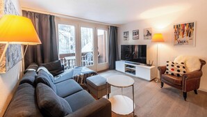Ein modernes Wohnzimmer mit einer Couch, einem Couchtisch, einem Fernseher und einem Sessel.