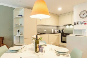 A modern kitchen with a dining area, equipped with a microwave, kettle, and a clock on the wall. - LuxuryYour Luxury Alpine Escape, Wallis 1070 (Wallis)