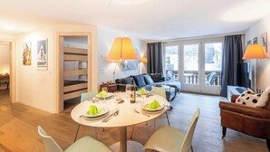 Ein helles, modernes Wohnzimmer mit Essbereich, Etagenbetten und einem Balkon mit Blick.