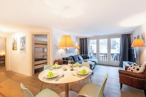 Ein helles, modernes Wohnzimmer mit Essbereich, Etagenbetten und einem Balkon mit Blick.