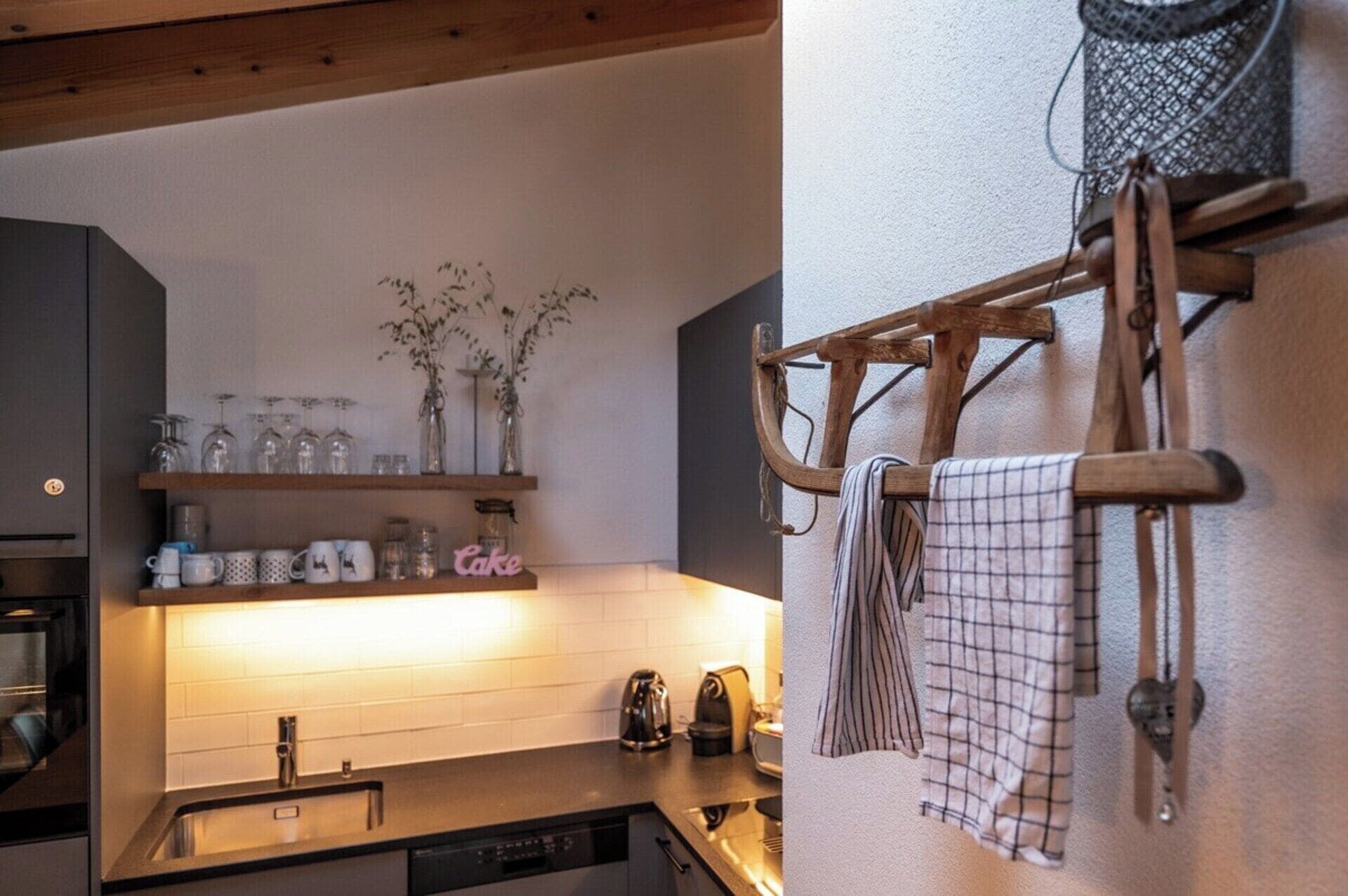 Een keuken met een houten plank met glazen en een ophangrek met handdoeken.