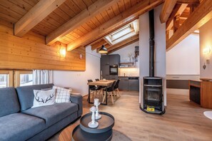 A cozy living room with a sofa, a dining table, and a fireplace. - Luxury Alpine Retreat, Wallis 1071 (Wallis)