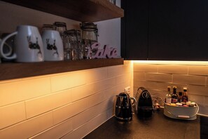 A kitchen with a shelf holding mugs and jars, a coffee maker, and a spice rack. - Luxury Alpine Retreat, Wallis 1071 (Wallis)