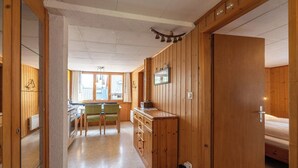 Habitación con paneles de madera, una kitchenette, zona de comedor y una cama.