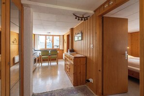 Ein Zimmer mit Holzwänden, einer Küchenzeile, einem Essbereich und einem Bett.