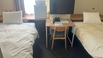 A hotel room with two single beds, a desk with a chair, a television, and a window with curtains.