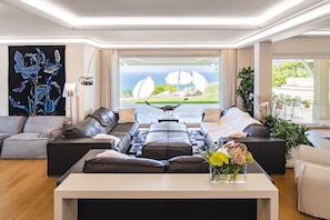 A modern living room with a sofa set, a coffee table, and a view of the ocean.