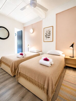 A hotel room with two beds, a ceiling fan, a framed leaf artwork, a bedside lamp, and a mirror. - Cozy apartment 150 meters from the beach (Les Trois-Îlets)
