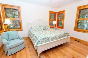 A bedroom with a bed, a chair, and two windows with shutters. - Soundside-ELEV, Priv pool, HTub, Rec Rm-CC328, Pipers Perch (Corolla)