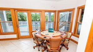 A poker table with chairs in a room with large windows and a view of a pool. - Soundside-ELEV, Priv pool, HTub, Rec Rm-CC328, Pipers Perch (Corolla)