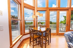 A dining area with a wooden table and chairs, large windows, and a view of the outdoors. - Soundside-ELEV, Priv pool, HTub, Rec Rm-CC328, Pipers Perch (Corolla)