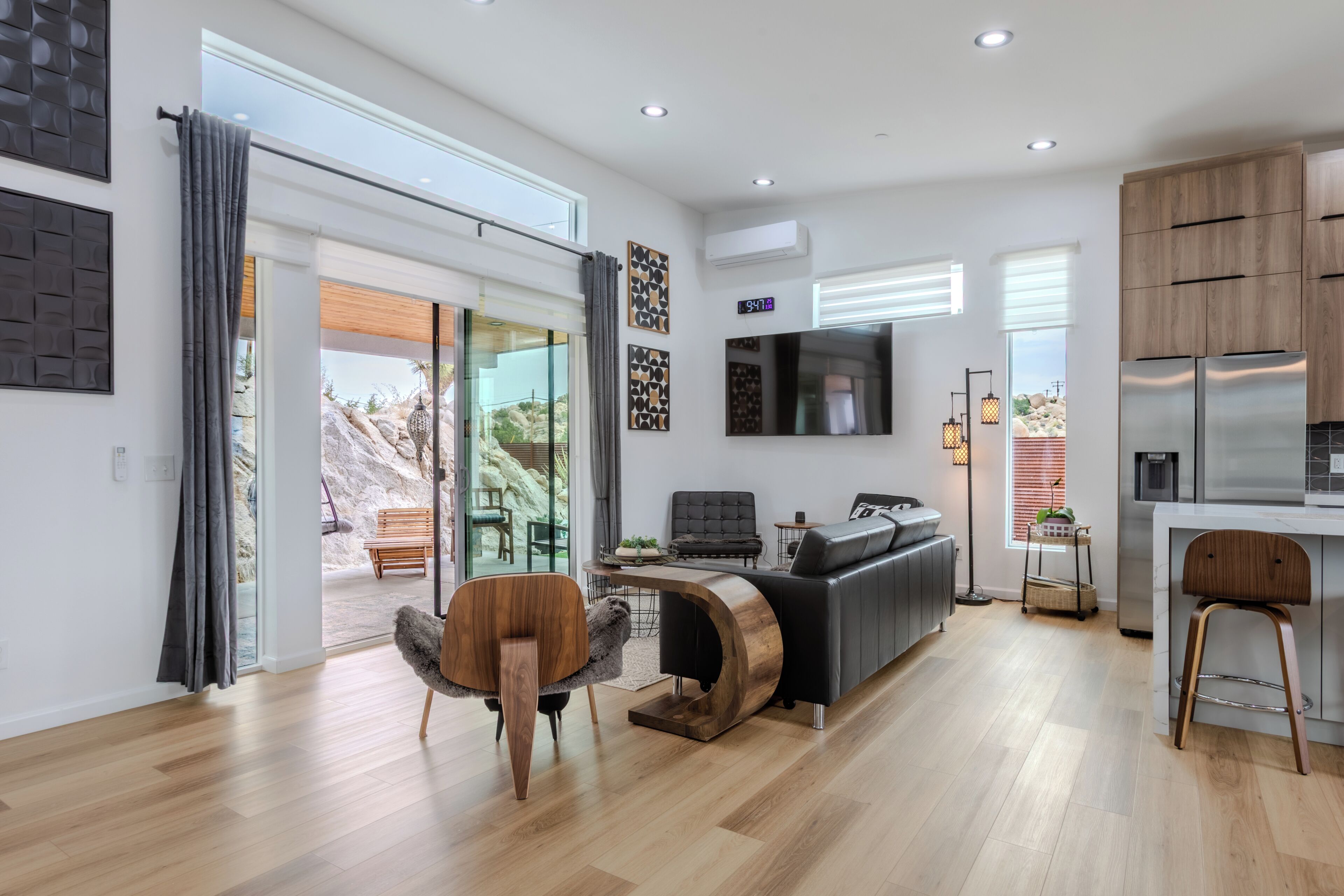 A modern living space with a sofa, a wooden coffee table, a television, and a kitchen area with a refrigerator.