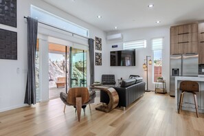 Ein stilvoller Wohnbereich mit einer Couch, einem Holztisch, einem Fernseher und einer Küchenzeile mit einem Kühlschrank.