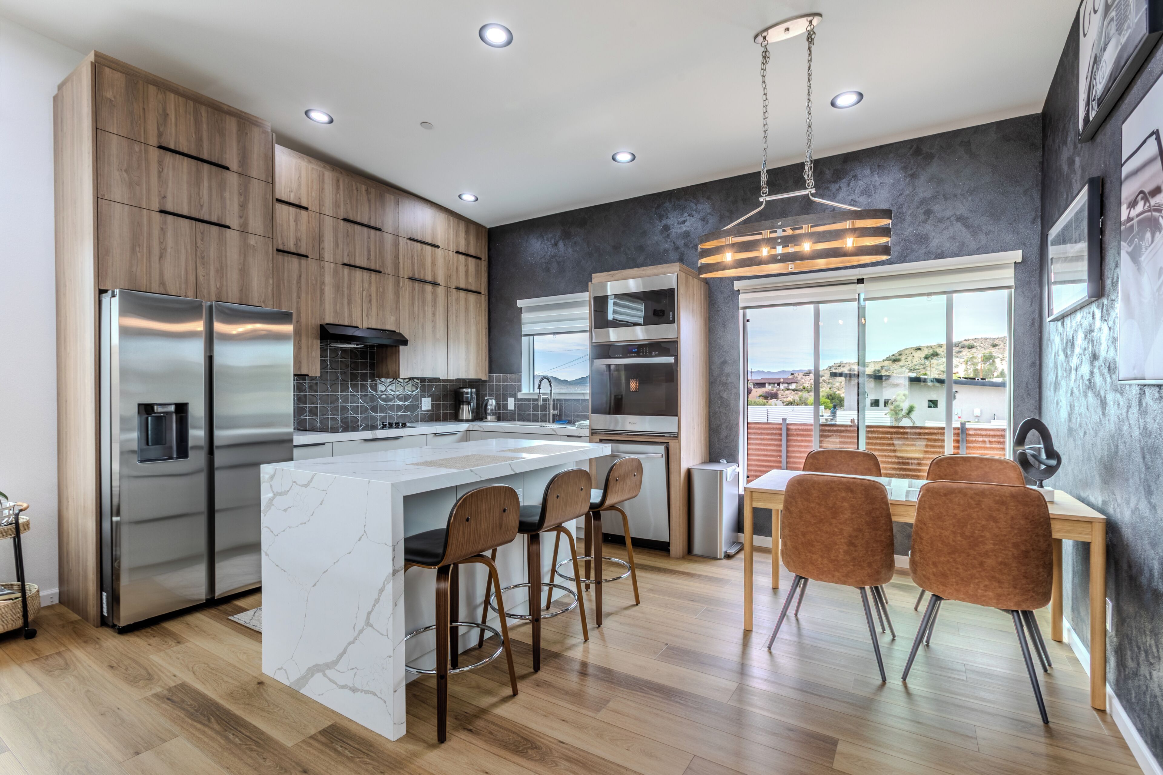A modern kitchen with a marble island, stainless steel appliances, and a dining area with bar stools.