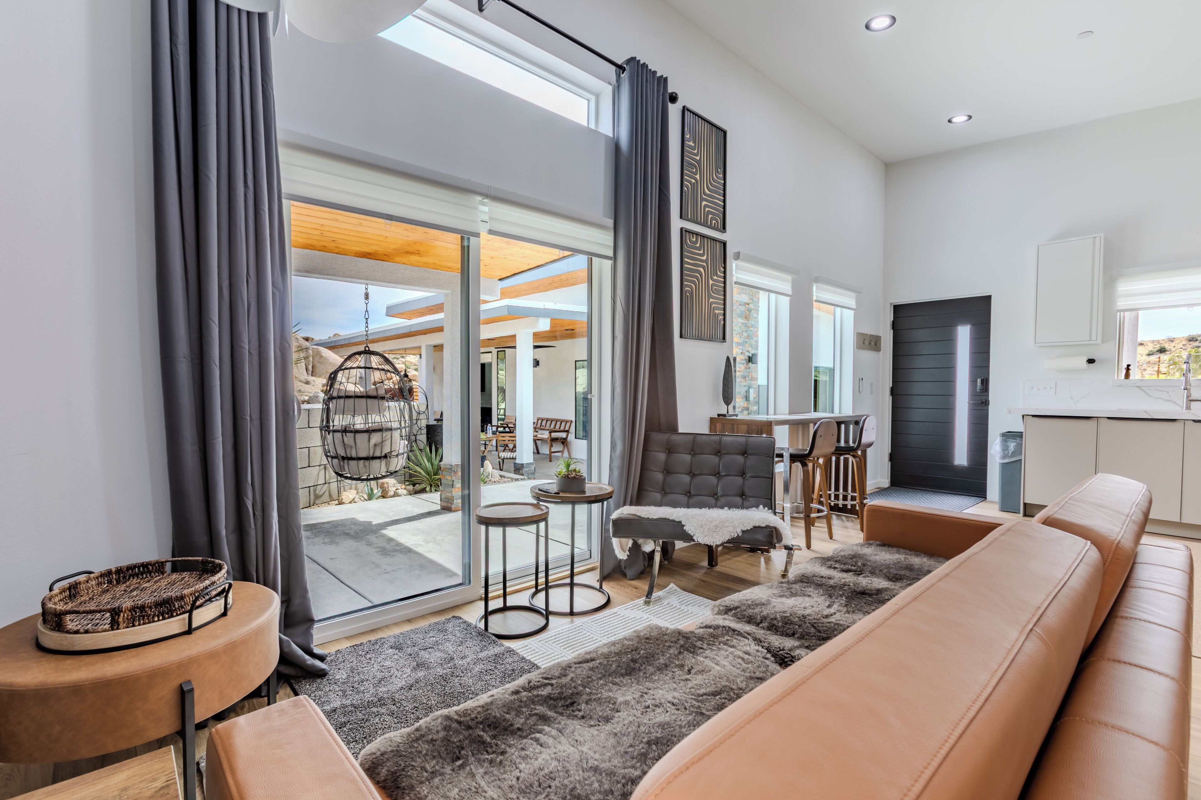 A modern living room with a sofa, a chair, a small table, and a large window.