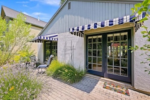 Ein Gebäude mit einer großen Glasdoor und einer Fußmatte. Vor der Tür steht ein Stuhl und ein Tisch.