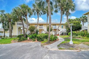 A residential building with multiple balconies, a paved driveway, and surrounding palm trees. - Sandpiper Cover 2020 - Near Beach - Sleeps 4 (Destin)