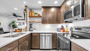 A modern kitchen with wooden cabinets, stainless steel appliances, and a built-in oven. - Sandpiper Cover 2020 - Near Beach - Sleeps 4 (Destin)