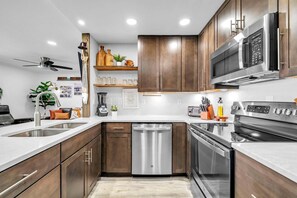 A modern kitchen with wooden cabinets, stainless steel appliances, and a built-in oven. - Sandpiper Cover 2020 - Near Beach - Sleeps 4 (Destin)