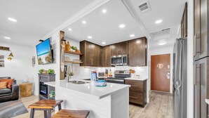 A modern kitchen with a central island, stainless steel appliances, and wooden cabinets. - Sandpiper Cover 2020 - Near Beach - Sleeps 4 (Destin)