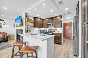 A modern kitchen with a central island, stainless steel appliances, and wooden cabinets. - Sandpiper Cover 2020 - Near Beach - Sleeps 4 (Destin)