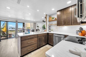 A modern kitchen with wooden cabinets, stainless steel appliances, and a view to the outside. - Sandpiper Cover 2020 - Near Beach - Sleeps 4 (Destin)