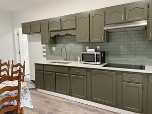 A kitchen with green cabinets, a microwave, and a sink.